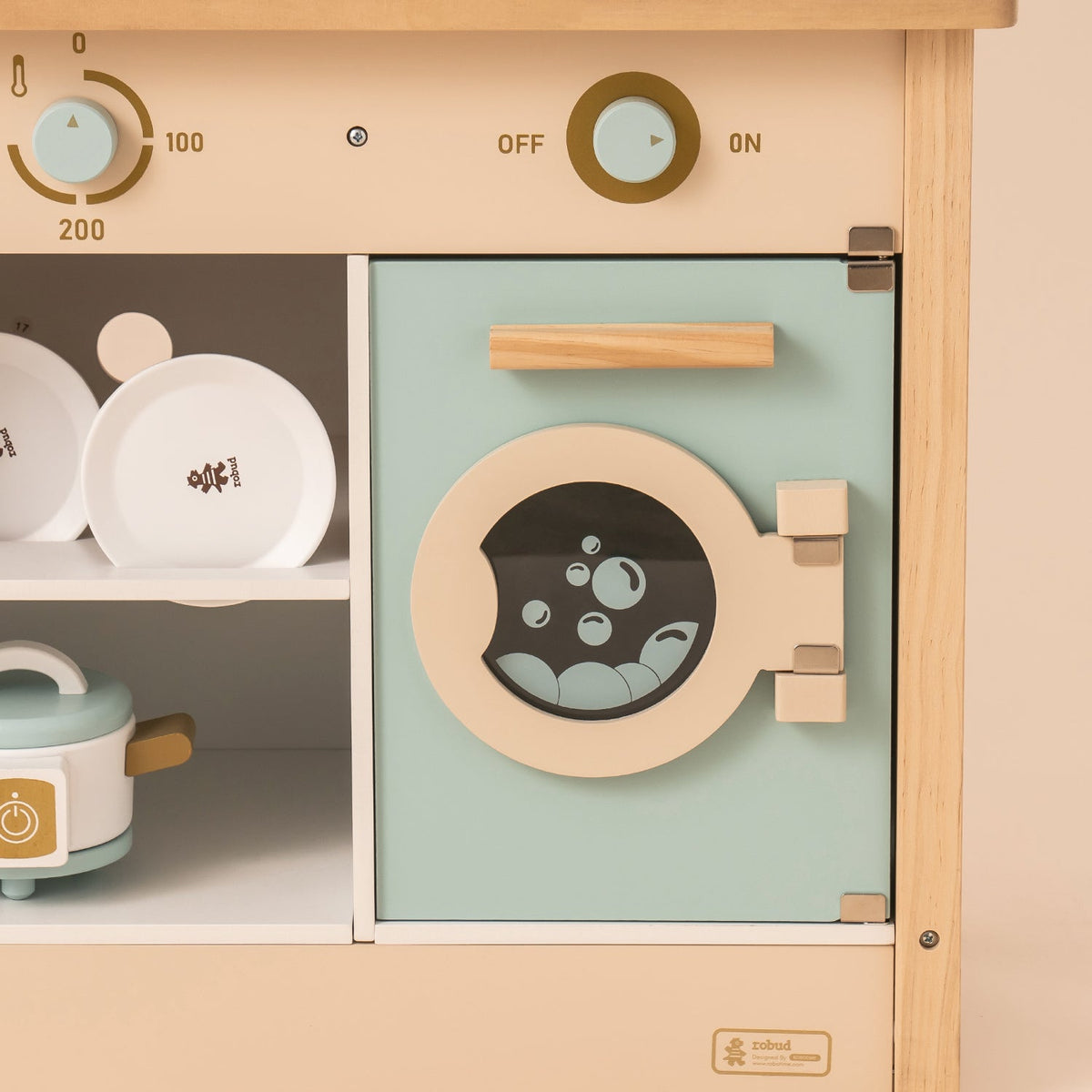 ROBUD kitchen washing machine panel detail with round porthole window, bubbles graphic and OFF control knob