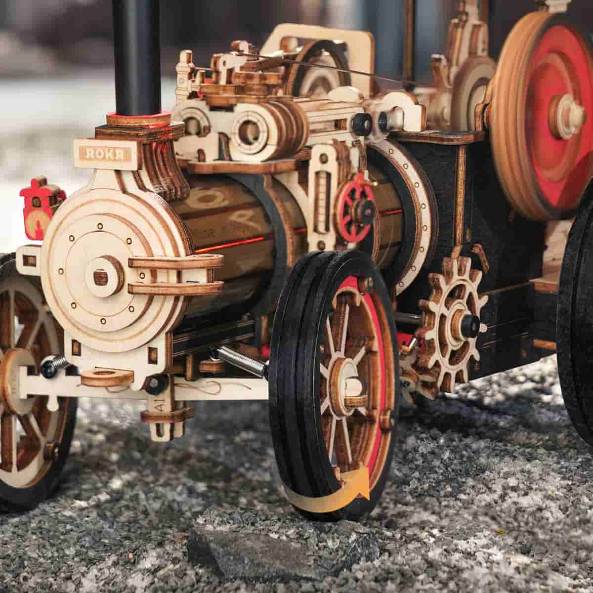 ROKR wooden steam locomotive close up showing red wheel, brake mechanism and weathered metal details
