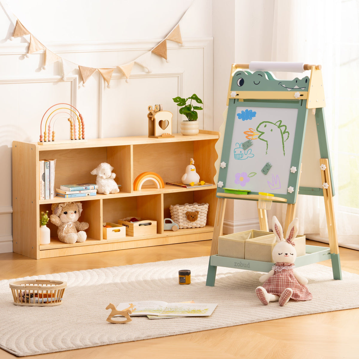 ROBUD green dino easel with whiteboard shown next to natural wood bookshelf and chairs in a Scandi children's room.