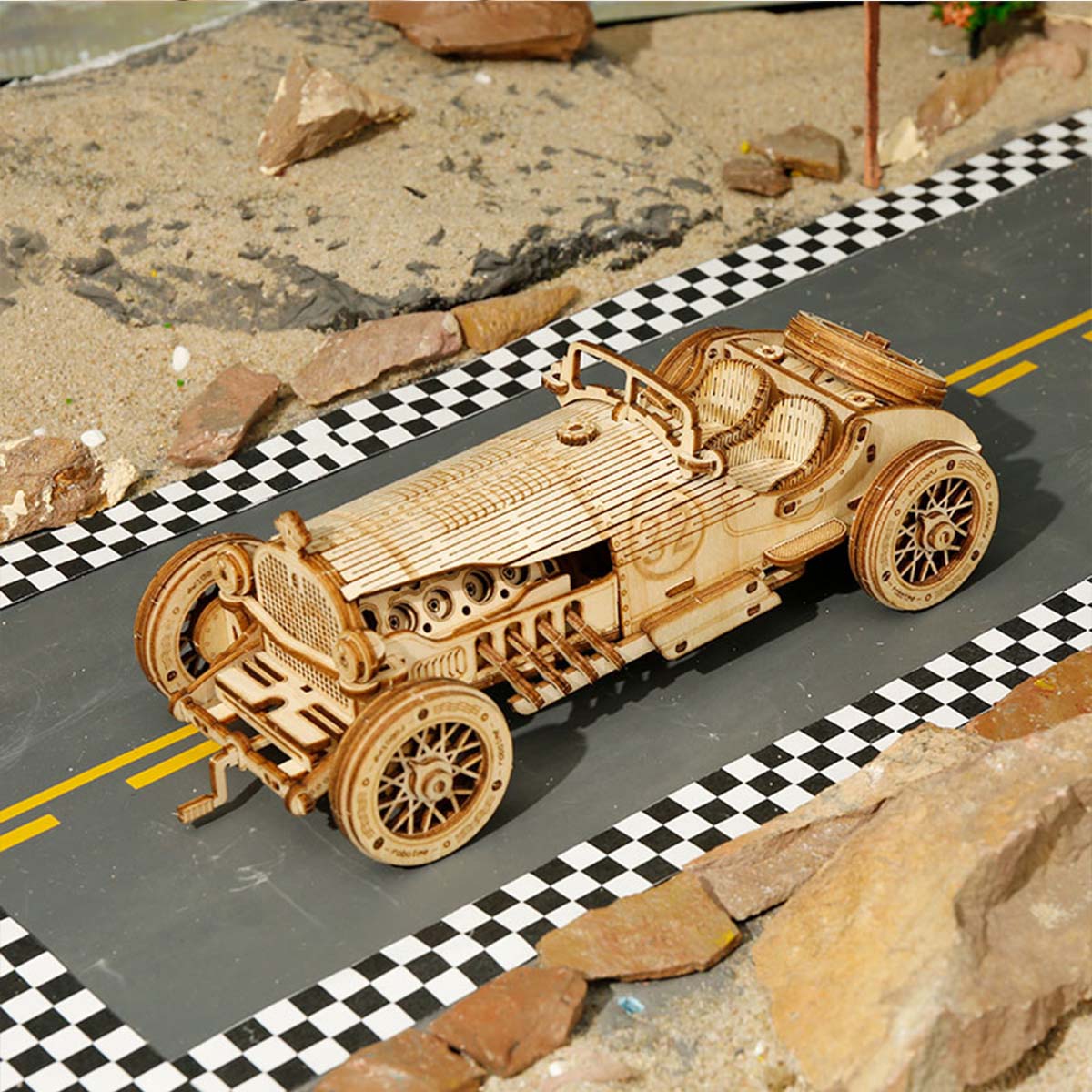 ROKR Grand Prix wooden race car assembled on a checkered track with rocky desert diorama background