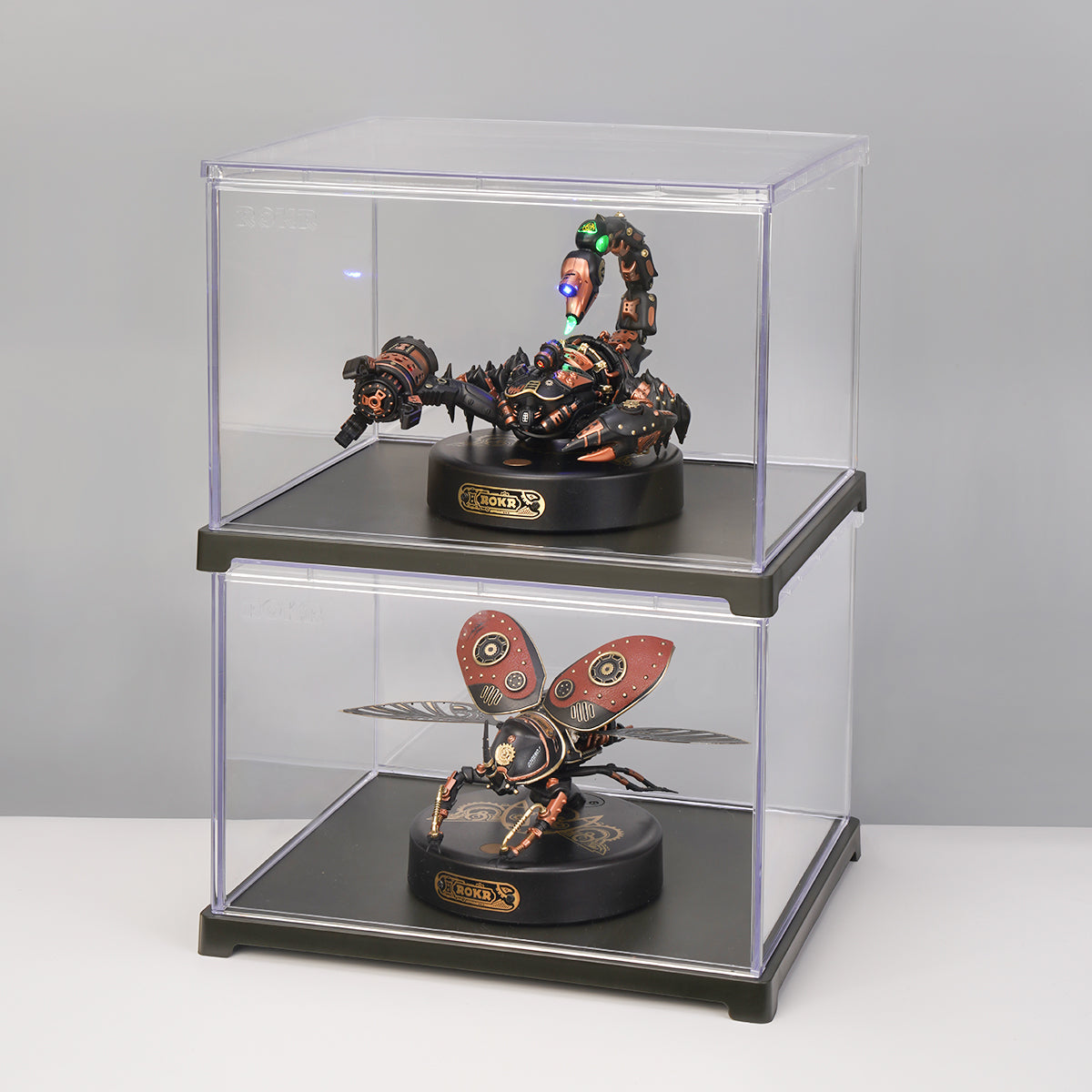 Two stacked clear acrylic cases each holding a ROKR steampunk scorpion and butterfly mechanical insect model