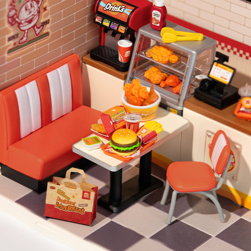 Rolife diner scene with burgers and fries on a table beside red booth seating and orange chair
