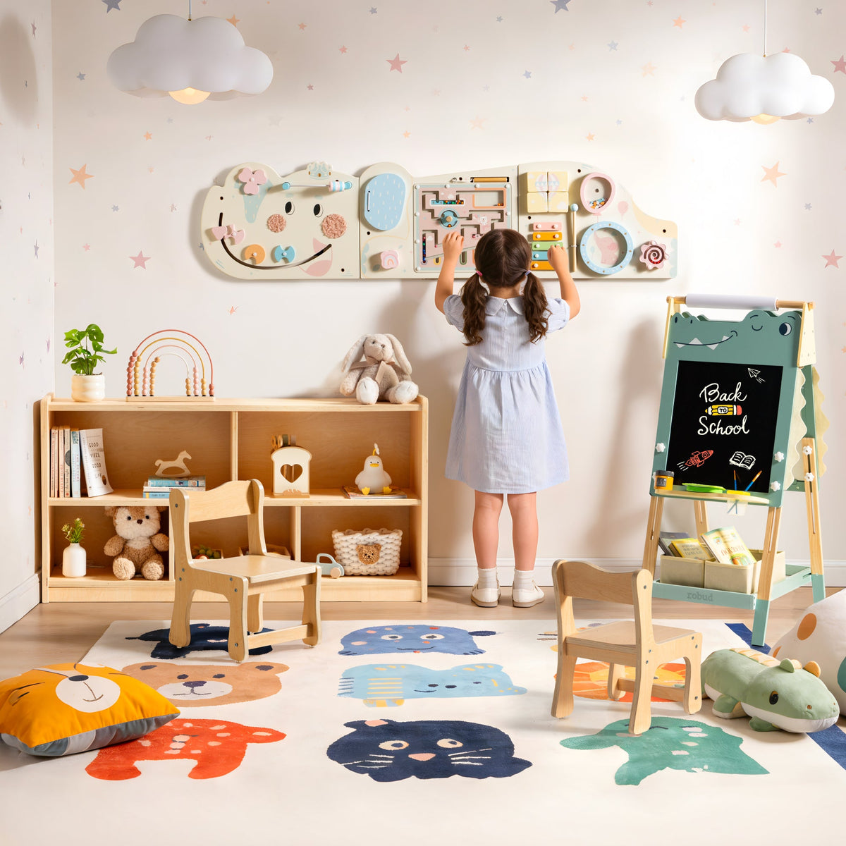 Young girl reaches up to the wall-mounted ROBUD sensory activity board while surrounded by bookshelf and easel furniture.
