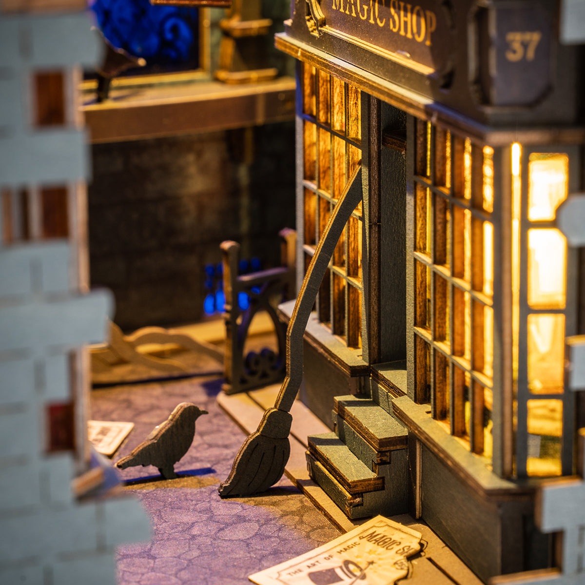 Rolife magic shop DIY book nook close up showing illuminated storefront, broomstick and cobblestone street